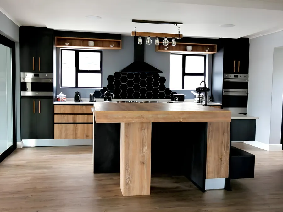 Charcoal kitchen cabinetry with an oak waterfall island and hexagon tile splashback, fitted by N.D.I.